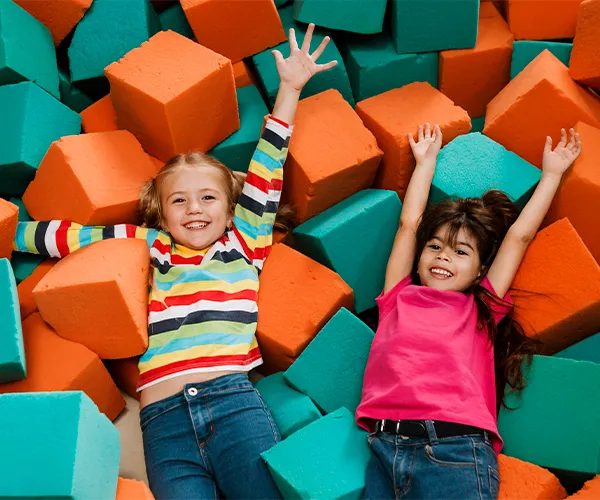 Kids laughing in a ball pit at Kiztopia